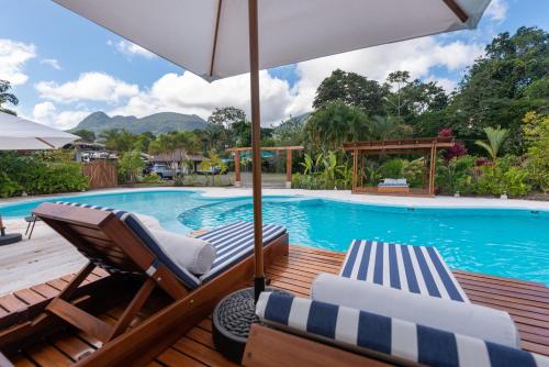 a swimming pool with two lounge chairs and an umbrella at Arenal History INN in Fortuna