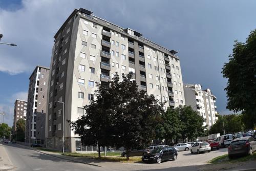 ein großes weißes Gebäude mit Autos auf einem Parkplatz in der Unterkunft Modern & Cozy in Skopje