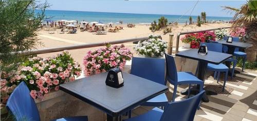 a row of tables and chairs on a balcony with a beach at White House in Tre Fontane