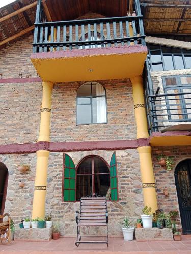 a bench sitting in front of a building with a balcony at Arte sin Fronteras Hostel in Paipa