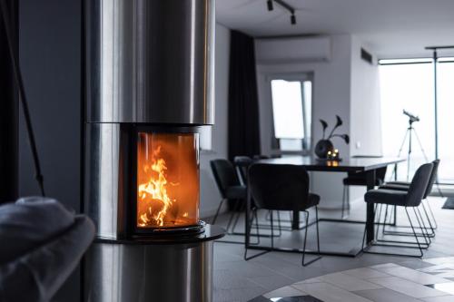 a fireplace in a living room with a table and chairs at Sky Garden Penthouse in Klaipėda