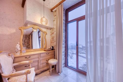 uma casa de banho com um espelho, uma cadeira e uma janela em Alpine Castle Hotel em Dilijan