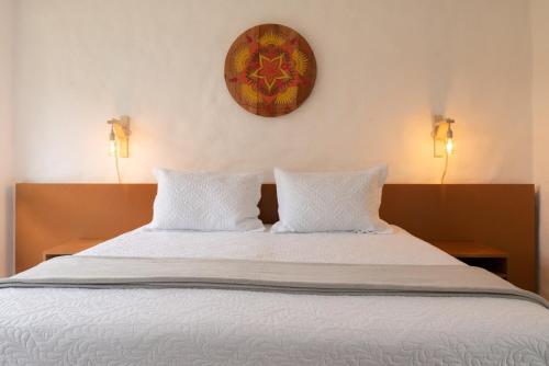 a bed with two pillows and a clock on the wall at Pousada Rosa Tropicalia in Praia do Rosa