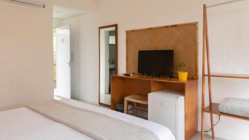 a bedroom with a desk with a television and a bed at Pousada Rosa Tropicalia in Praia do Rosa