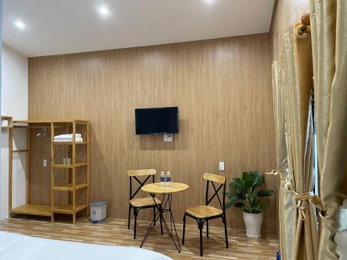 a room with a table and chairs and a tv on a wall at Pleiku Homestay in Pleiku