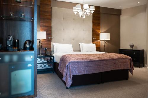バーミンガムにあるClayton Hotel Birminghamのベッドとシャンデリアが備わるホテルルームです。