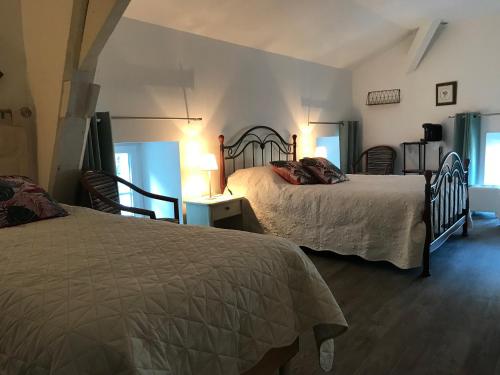 een slaapkamer met 2 bedden en 2 stoelen bij MOULIN DE L'ABBESSE in Thouars