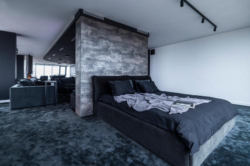 een slaapkamer met een groot bed en een bakstenen muur bij Sky Garden Penthouse in Klaipėda