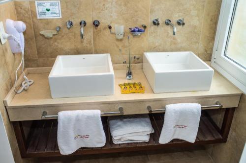 een badkamer met 2 wastafels en handdoeken op een plank bij Playa Gaviota Suites Apart in Las Gaviotas