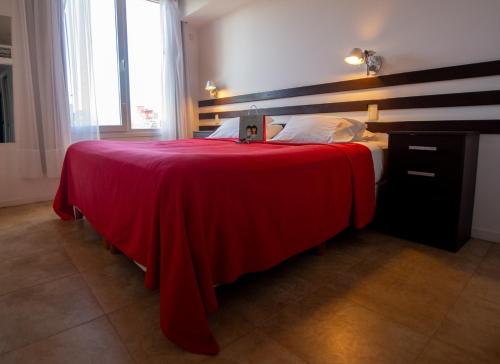 Una cama con una manta roja en una habitación en Playa Gaviota Suites Apart en Las Gaviotas