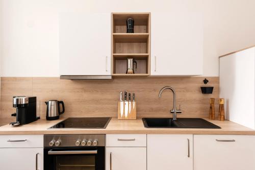 une cuisine avec des armoires blanches et un évier dans l'établissement 90sqm 2BR Biz LOFT - 5min Central Station, à Berlin