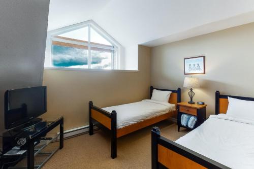 a room with two beds and a tv and a window at Trappers Crossing 22 in Big White
