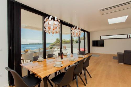 une salle à manger avec une grande table et des chaises en bois dans l'établissement Villa Garma Beachfront - 3 Bedroom villa - Stunning Sea Views - Gym - Private Pier, à Potirna