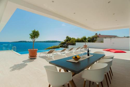 une salle à manger avec une table bleue et des chaises blanches dans l'établissement Villa Garma Beachfront - 3 Bedroom villa - Stunning Sea Views - Gym - Private Pier, à Potirna