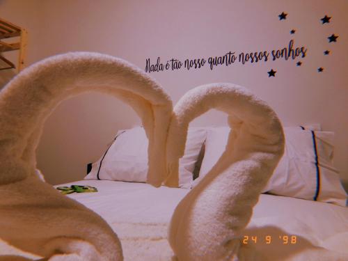a bed with two towel animals on it with a alarm clock at BORA BORA RESIDENCE in Joinville