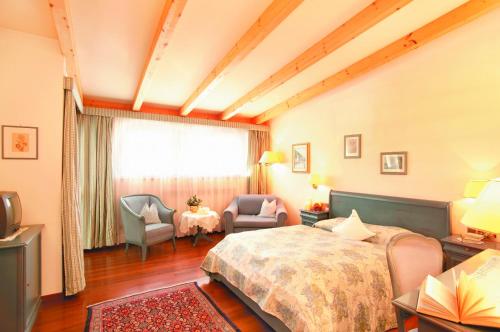 una camera d'albergo con un letto, sedie e una finestra di Hotel Tschurtschenthaler a Dobbiaco