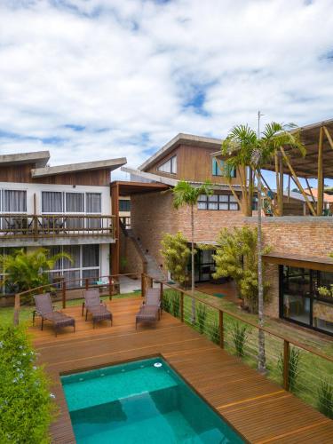 an outdoor deck with a swimming pool and a house at Pousada Rosa Tropicalia in Praia do Rosa