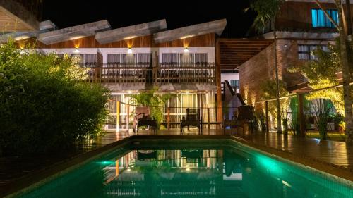 a swimming pool in front of a building at night at Pousada Rosa Tropicalia in Praia do Rosa