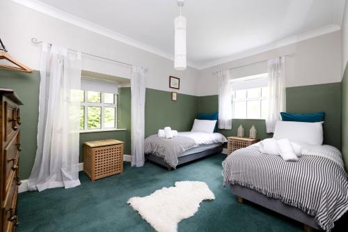 ドライメンにあるStrathendrick House Magnificent property with Gardenの緑と白の部屋のベッド2台