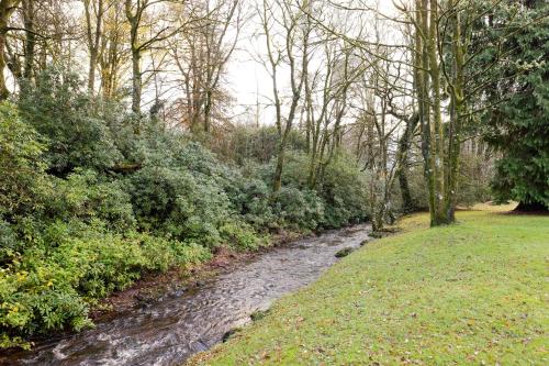 a stream in the middle of a field with trees at Strathendrick House Magnificent property with Garden in Drymen
