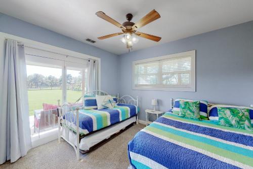 een slaapkamer met 2 bedden en een plafondventilator bij Packsaddle Beach House in Rockport