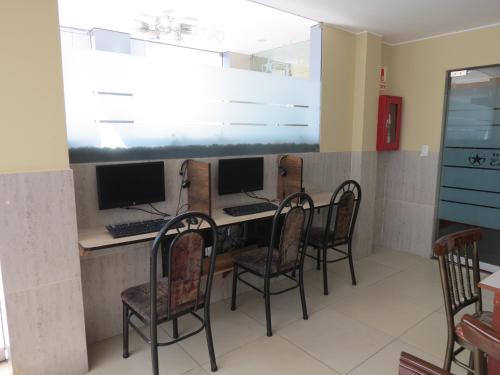 a room with a desk with three monitors and chairs at HOTEL ESTRELLA in Lima