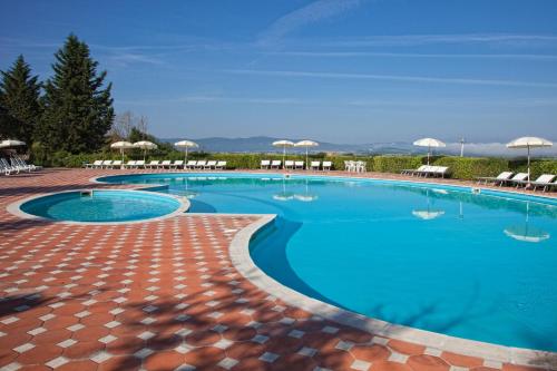 a large swimming pool with chairs and umbrellas at Fattoria Pieve a Salti in Buonconvento