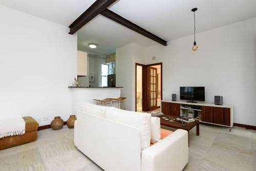 uma sala de estar com um sofá branco e uma televisão em Varanda a 500m da praia de Ipanema e 100m da Lagoa no Rio de Janeiro