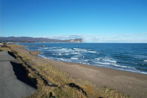 a beach with the ocean and a mountain in the distance at MATRYOSHKA HOUSE in Yoichi