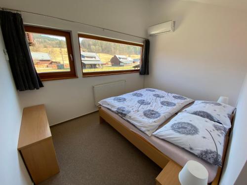 a small bedroom with a bed and two windows at Apartmany Resort in Horní Bečva