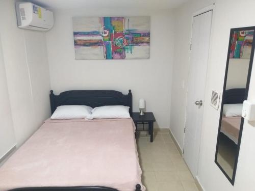 un pequeño dormitorio con una cama y una pintura en la pared en Apartamento Rodadero, Edificio Palanoa 308 en Santa Marta