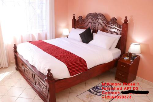 a bedroom with a large bed with a wooden frame at Milimani Furnished Apartments in Nakuru