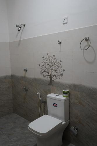 a bathroom with a toilet with a tree on the wall at Laguna Surfing Stay in Midigama
