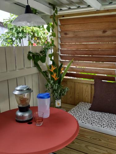 een rode tafel met een drankje op een patio bij Private Garden Suite, Surf, Work, Relax in Christ Church