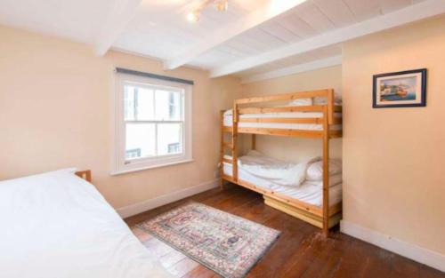 a bedroom with two bunk beds and a window at Jacobs Cottage in Port Isaac