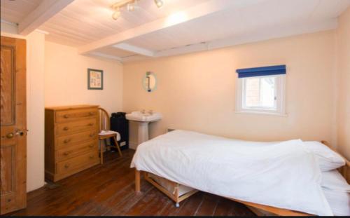a bedroom with a white bed and a sink at Jacobs Cottage in Port Isaac