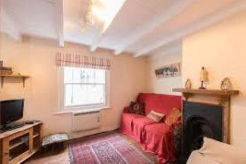 a living room with a red couch and a window at Jacobs Cottage in Port Isaac