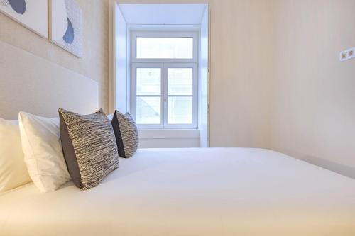 a white bed with two pillows and a window at Ando Living - Douradores House in Lisbon