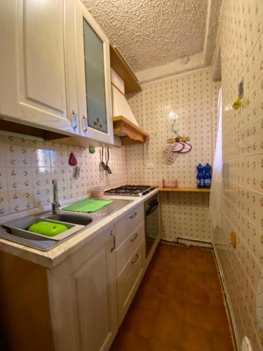 una pequeña cocina con armarios blancos y fregadero en Bellavista 5 Confini en Terminillo