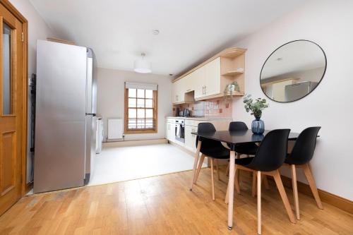 a kitchen with a table and chairs and a refrigerator at JOIVY Bright and Cosy Flat near The Scotland Gallery in Edinburgh