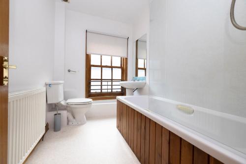 a bathroom with a tub and a toilet and a sink at JOIVY Bright and Cosy Flat near The Scotland Gallery in Edinburgh