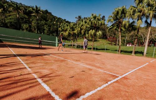 three people playing tennis on a tennis court at Plaza Caldas da Imperatriz Resort & Spa in Santo Amaro da Imperatriz