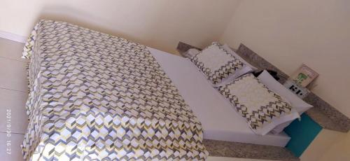 a bed with a comforter and pillows on it at Hotel & Motel ap Aparecida de Goiânia in Aparecida de Goiania