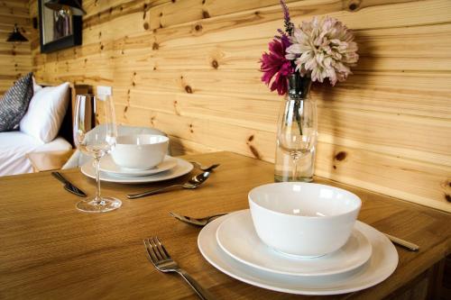 a wooden table with two plates and a vase with flowers at Lily in Rhayader