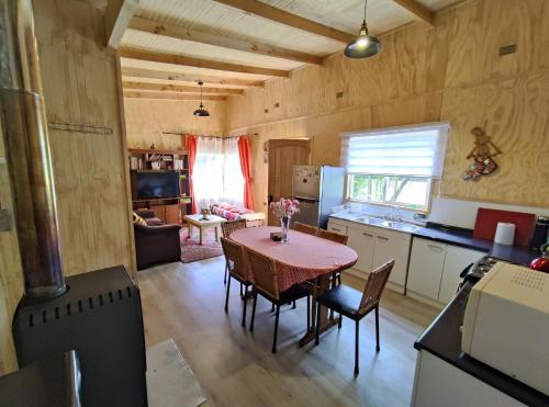 a kitchen and dining room with a table and chairs at Cabañas Koyam in Melipeuco