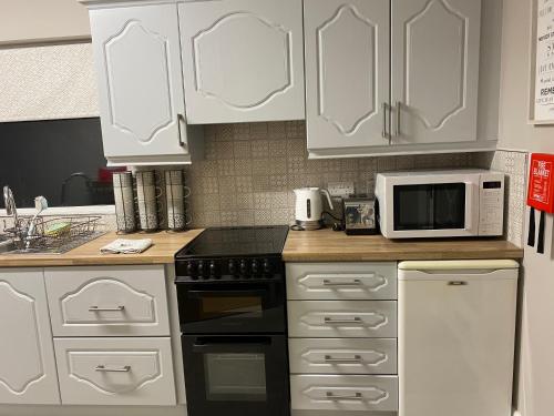 a kitchen with white cabinets and a stove and a microwave at Big Anthony’s in Greencastle