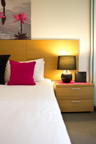 a bedroom with a bed with a red pillow and a lamp at Cairns Private Apartments in Cairns