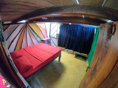 Habitación pequeña con cama roja en una yurta en Reciclarte Galería Hostal en Capurganá