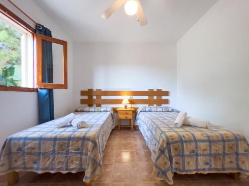 a bedroom with two beds and a table with a lamp at Can Pep Yern 2 in Playa Migjorn