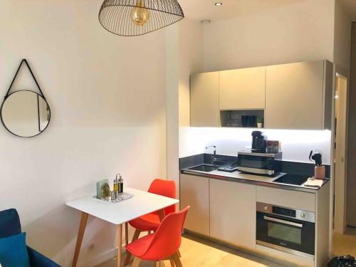 une petite cuisine avec une table blanche et des chaises rouges dans l'établissement Homelivia, Votre Appartement ideal pour découvrir Nice, à Nice